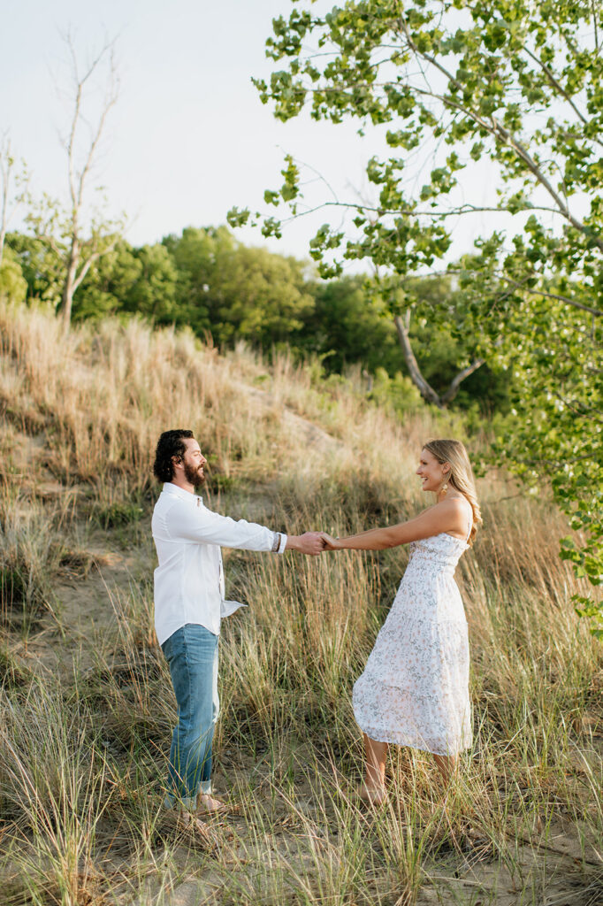 Couple being playful in the beach grass for their Indiana Dunes State Park engagement photos