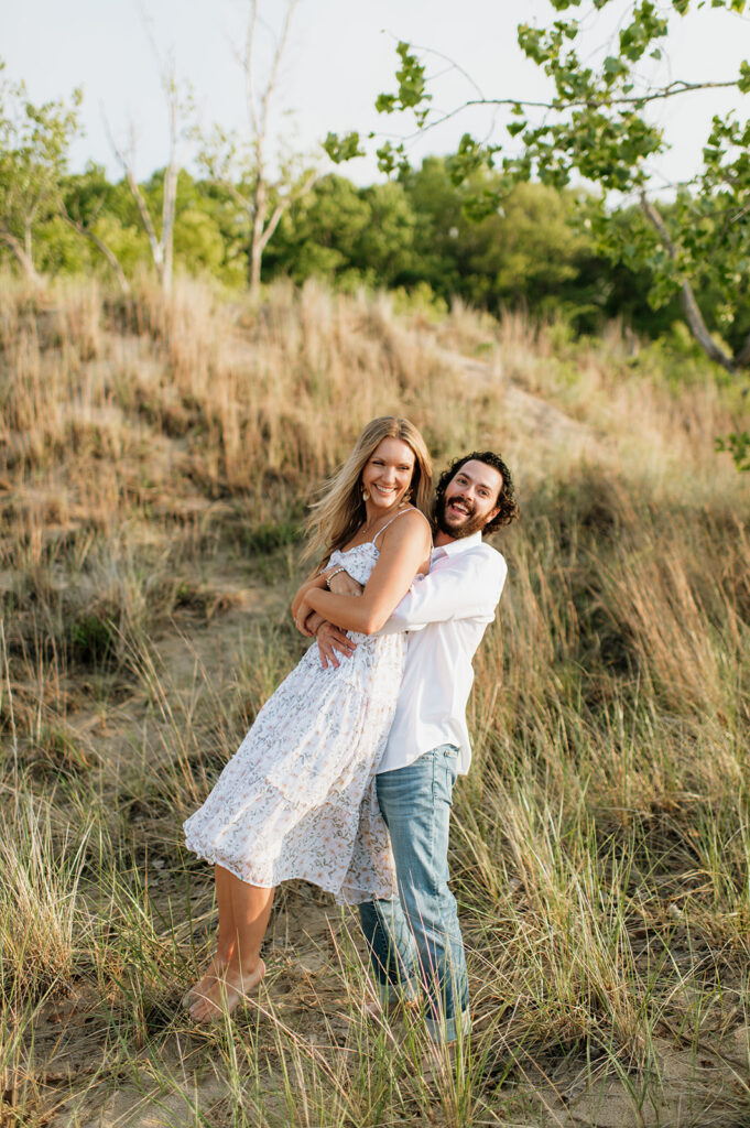 Couple being playful in the beach grass for their Indiana Dunes State Park engagement photos