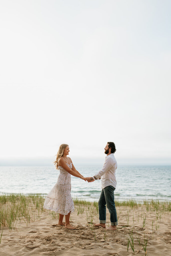 Couple posing on top of a hill for their beach engagement photos at Indiana Dunes State Park