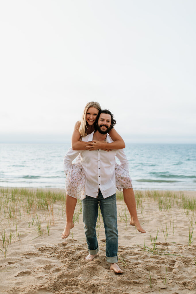 Man giving his fiancé a piggy-back ride on the beach