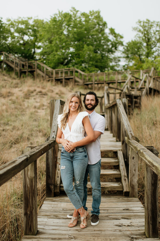 Couple posing on a boardwalk staircase for their Indiana Dunes National Park engagement photos