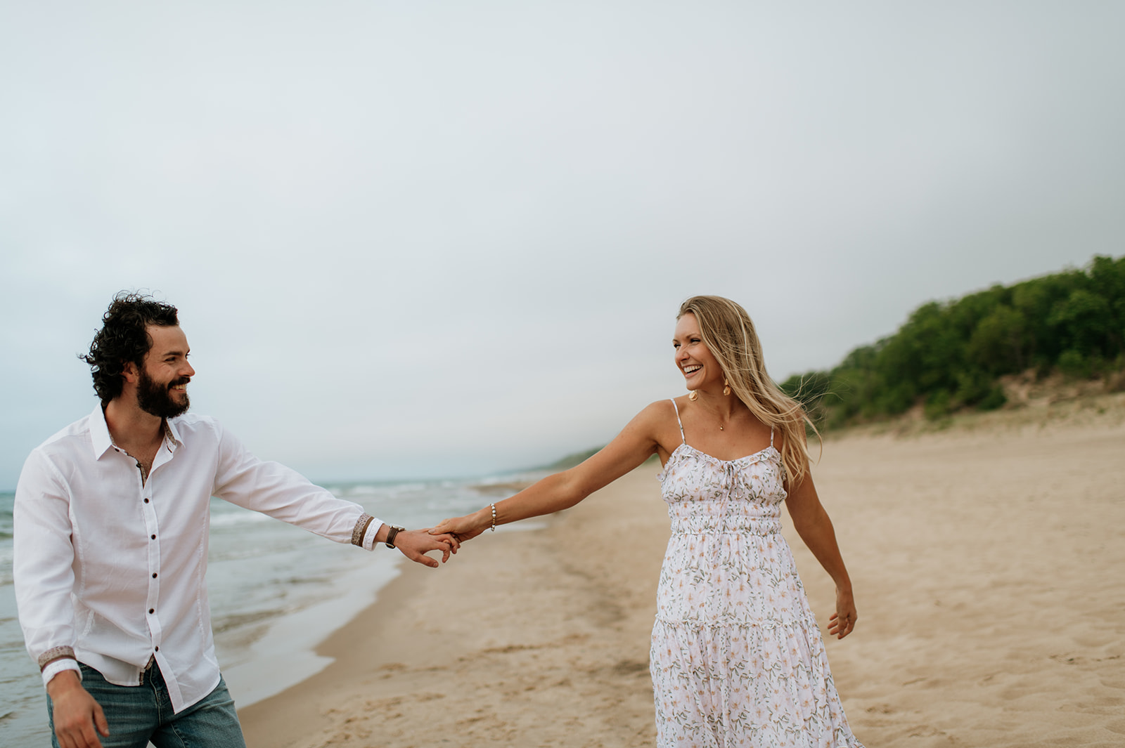 Couple walking along the shoreline at Indiana Dunes National Park for their beach engagement photos