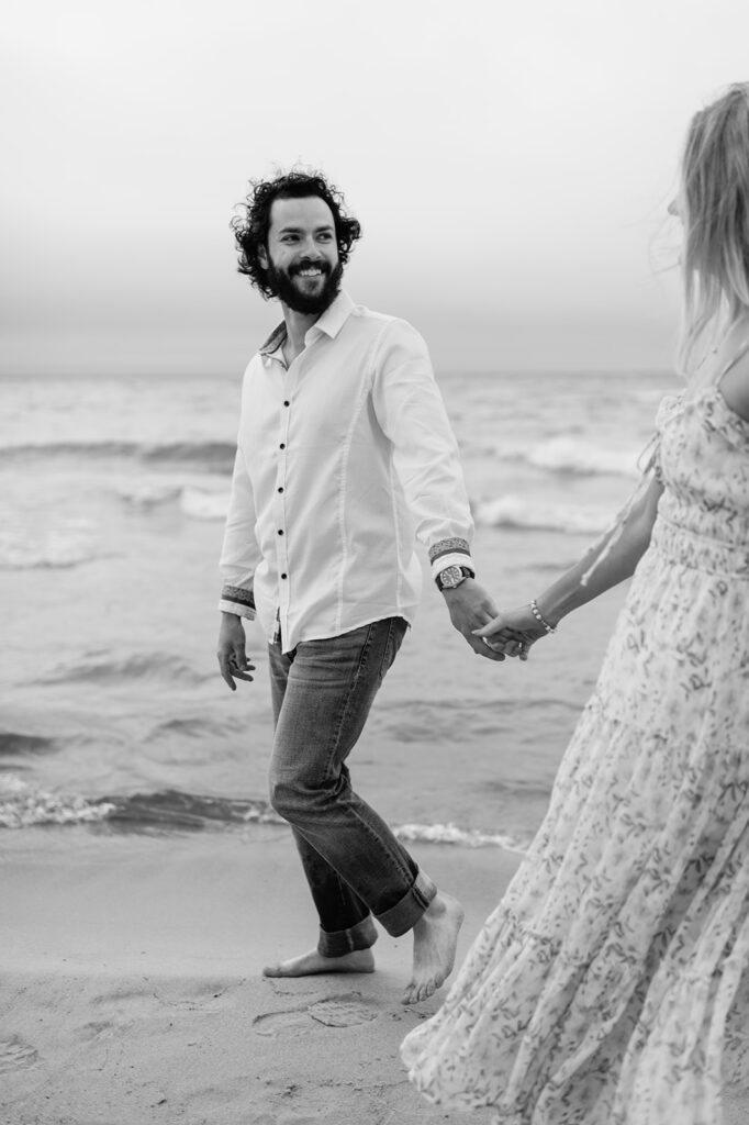 Couple walking along the shoreline at Indiana Dunes National Park for their beach engagement photos