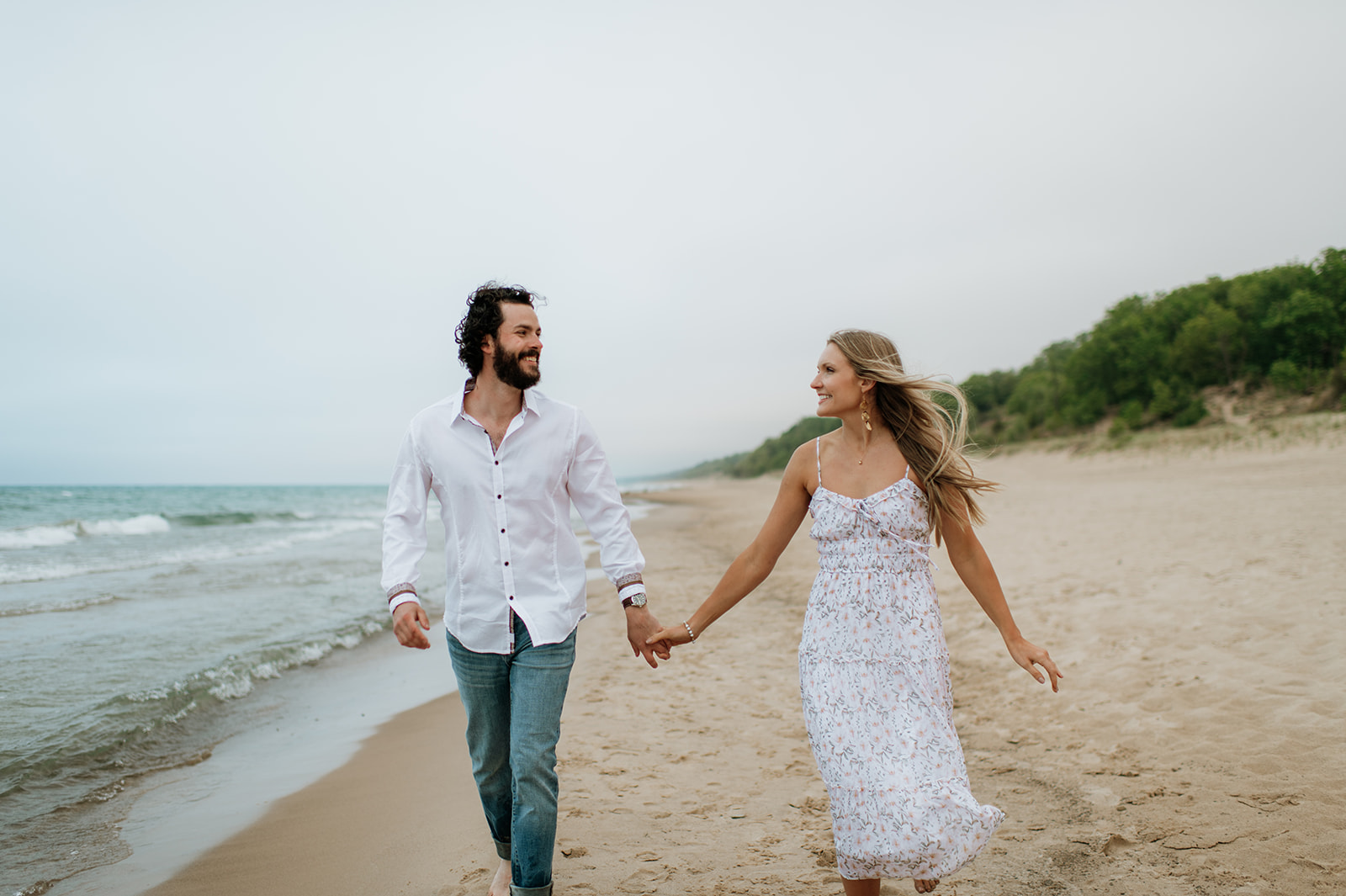 Couple walking along the shoreline at Indiana Dunes National Park for their beach engagement photos