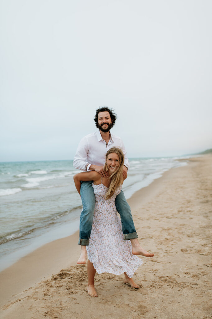 Woman giving her fiancé a piggy back ride on the beach