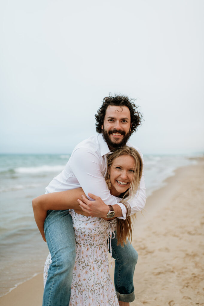 Woman giving her fiancé a piggy back ride on the beach