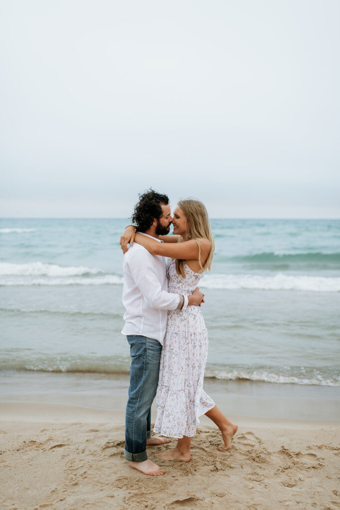 Couple touching noses during their summer beach engagement photos in Indiana