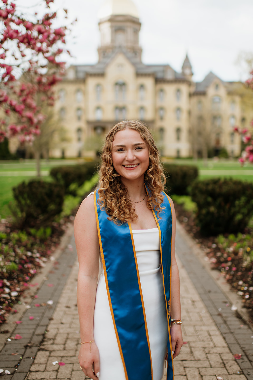 Graduate posing in front of The Golden Dome