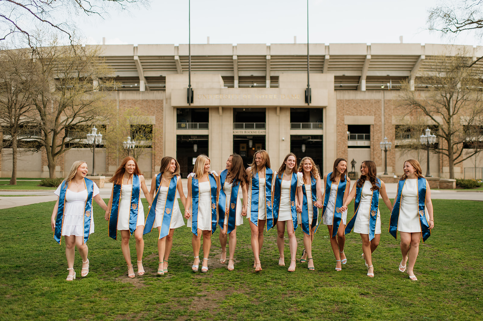 11 University of Notre Dame grads posing in front of the stadium 
