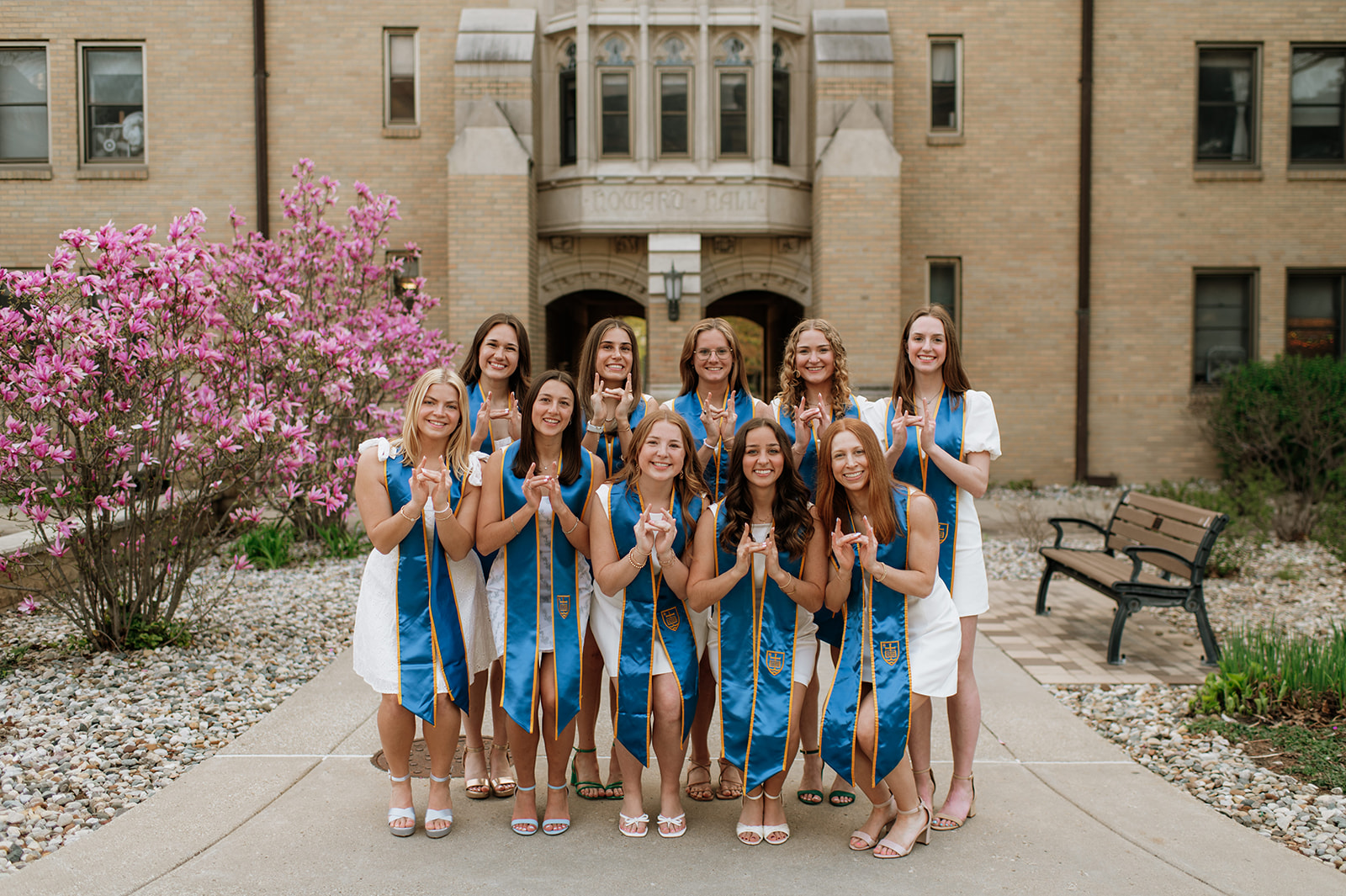 11 graduates making a university of Notre Dame hand signal