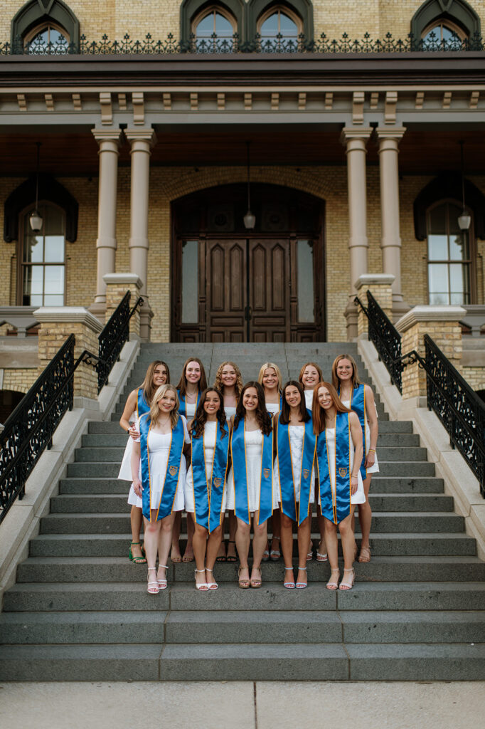 11 Notre Dame University grad students posing for their graduation photos on the Main Building Steps