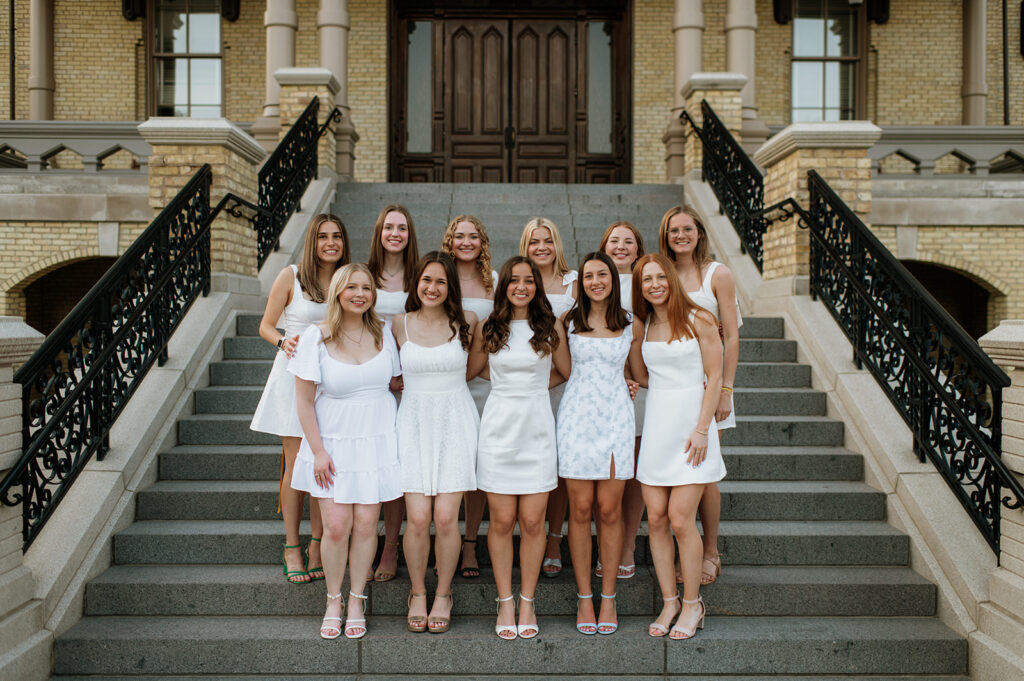 11 grads posing on the main building steps