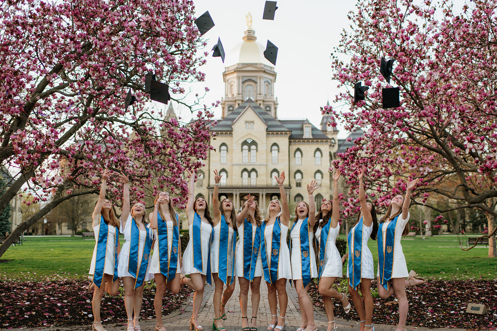 University of Notre Dame graduates throwing their caps in front of The Golden Dome