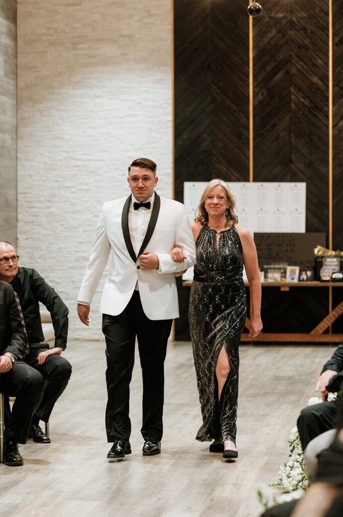 Groom walking down the aisle with his mother