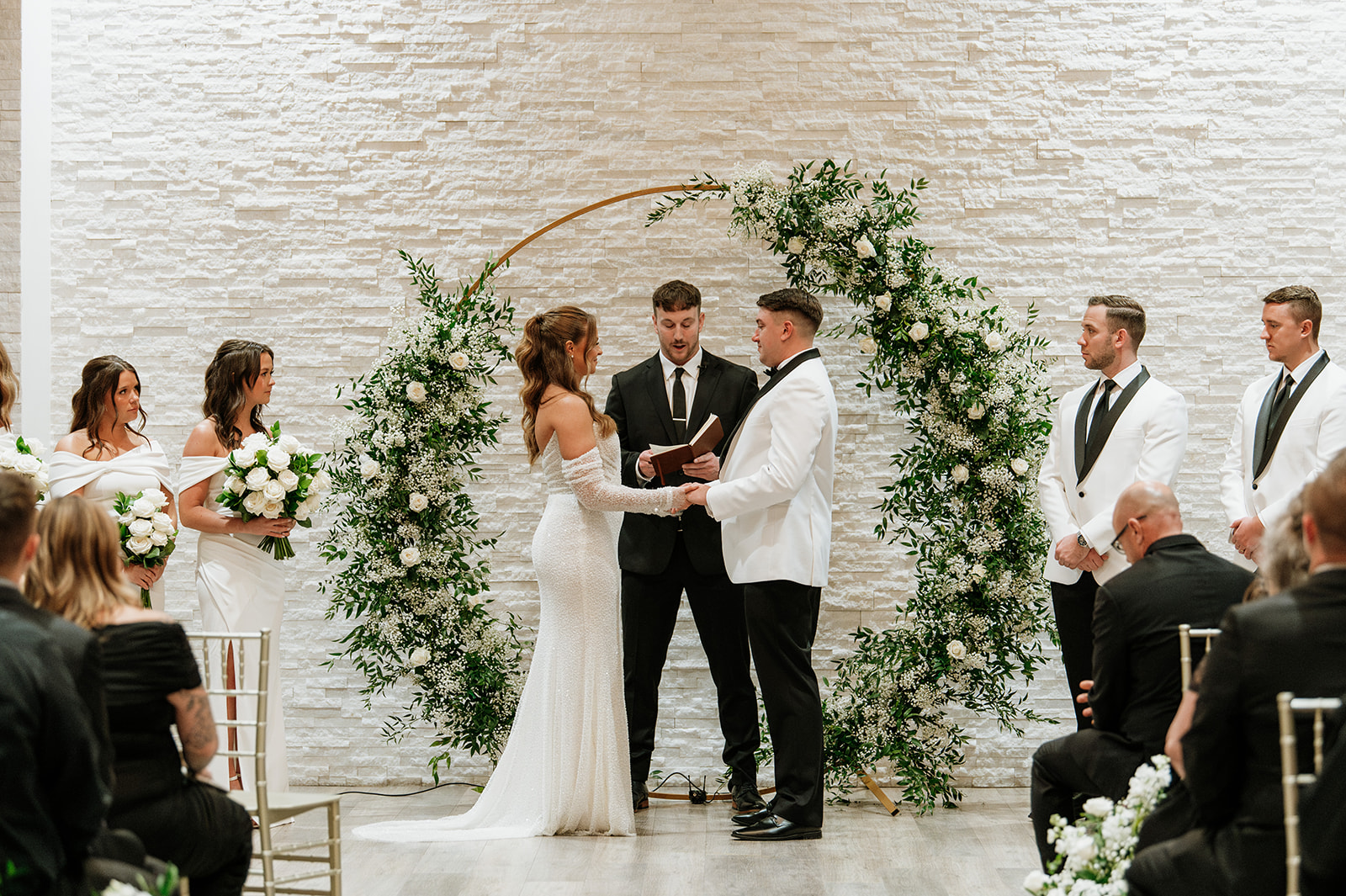 Bride and groom holding hands during their indoor winter wedding ceremony