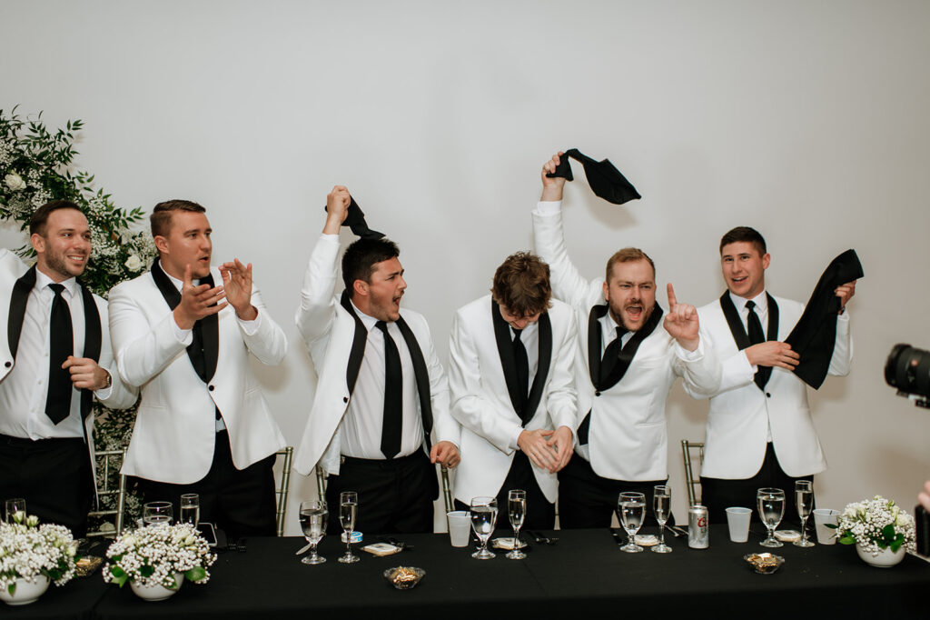 Groomsmen waving towels as the bride and groom enter their wedding reception