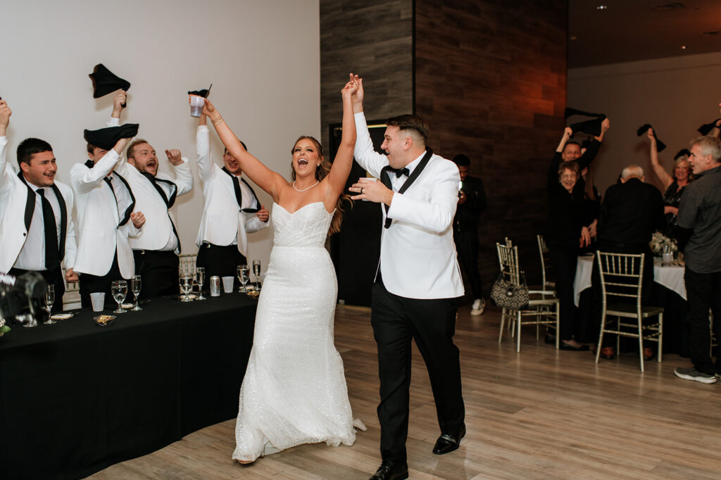 Groomsmen waving towels as the bride and groom enter their wedding reception