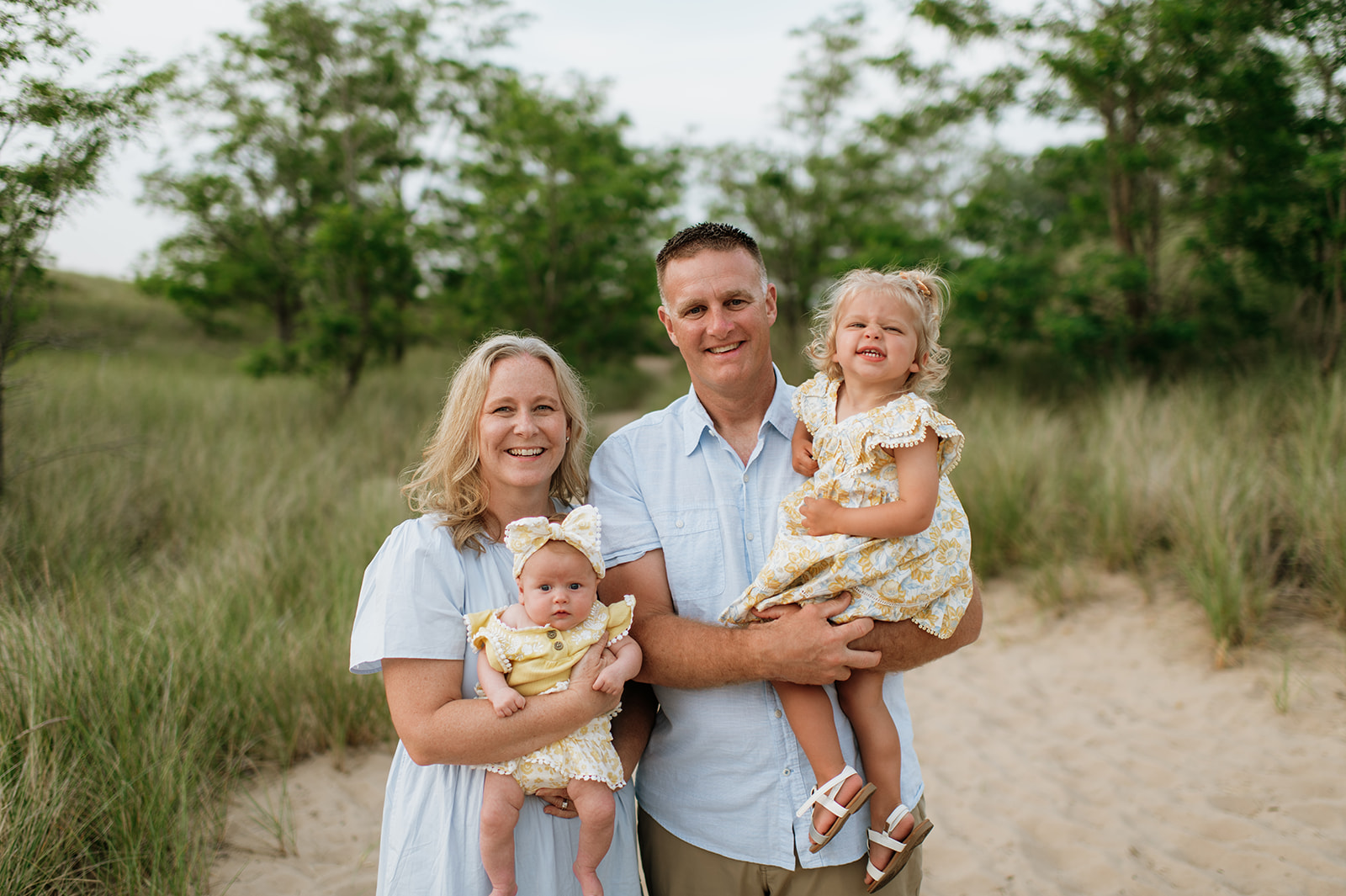 Grandparents holding their granddaughters during their outdoor extended family photoshoot on New Buffalo Beach in Michigan