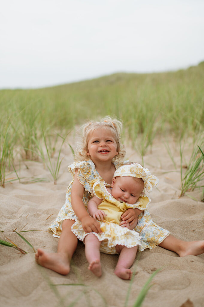 Toddler and baby siblings posing together on the beach in New Buffalo, Michigan