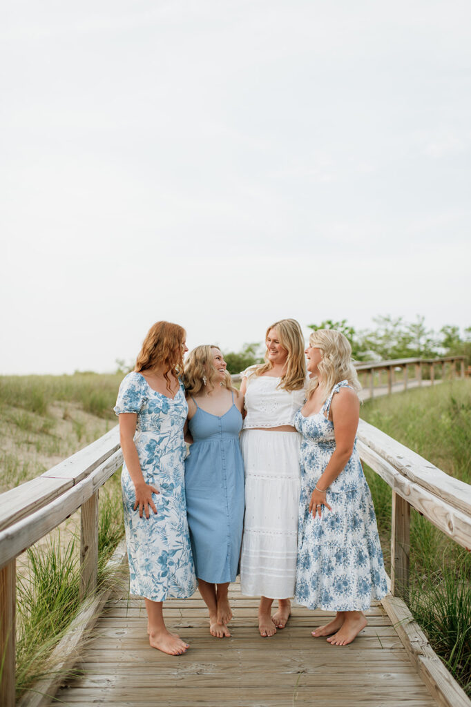 Four sisters posing on a boardwalk for their extended family photoshoot in Southwest Michigan