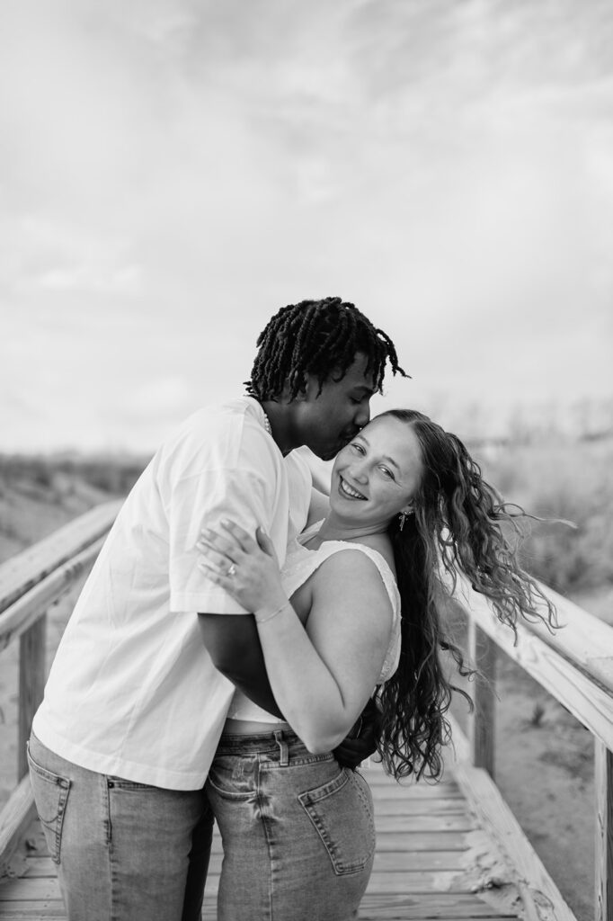 Black and white photo of a couple kissing on the boardwalk for their Southwest Michigan engagement photos at New Buffalo Beach