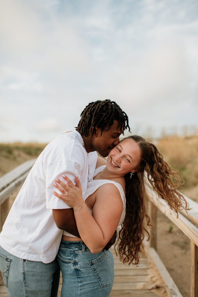 Man kissing his fiance on the boardwalk at New Buffalo beach in Michigan