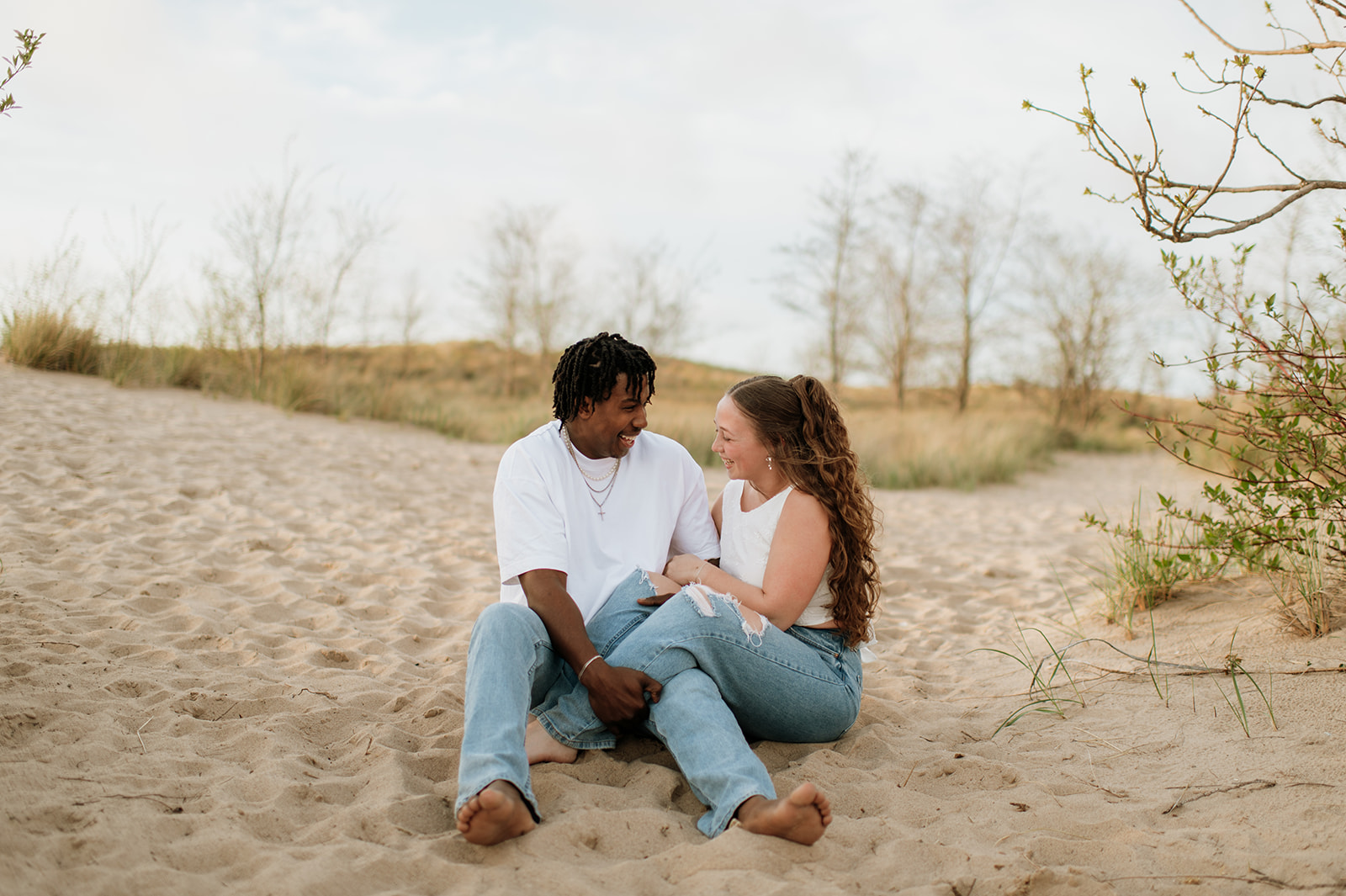 Couple laughing while sitting in the sand on New Buffalo beach in Southwest Michigan