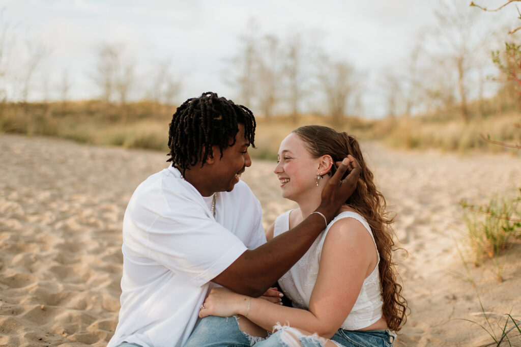 Man moving the hair out of his fiancés face during their beach engagement session