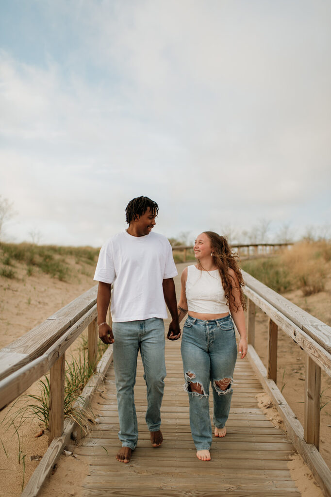 Couple holding hands and walking the boardwalk at New Buffalo Beach in Southwest Michigan
