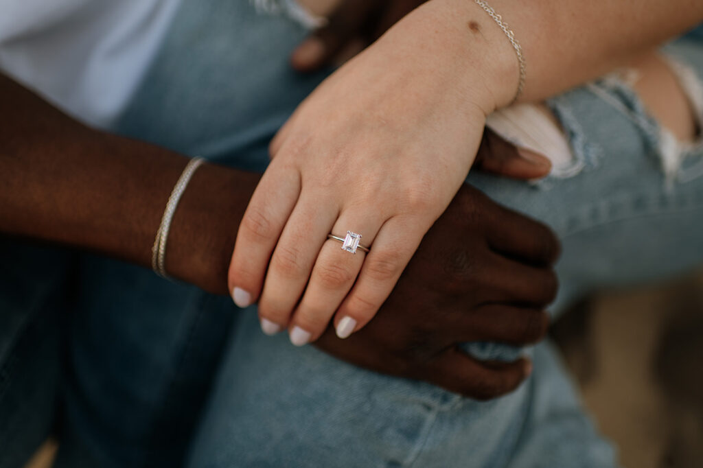 Engagement photo detail shot of a couple holding hands over one another and showing off the engagement ring