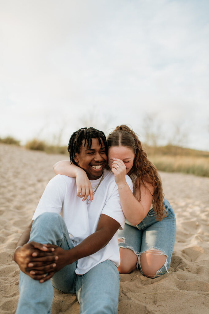 Couple laughing while sitting in the sand on New Buffalo beach in Southwest Michigan