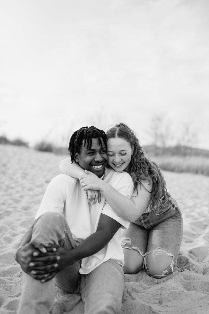Black and white photo of a couple laughing on New Buffalo beach for their Southwest Michigan engagement photos