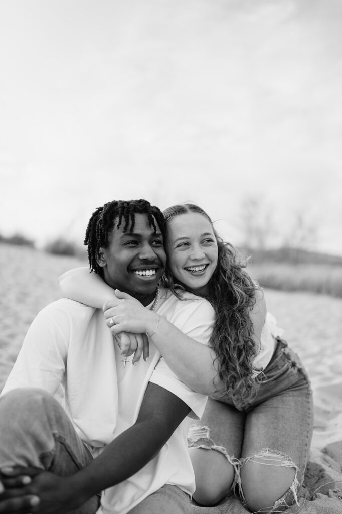Black and white photo of a couple laughing on New Buffalo beach for their Southwest Michigan engagement photos