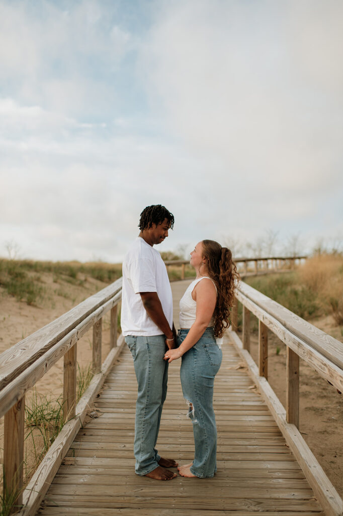 Couple posing on the boardwalk for their Southwest Michigan engagement photos at New Buffalo Beach