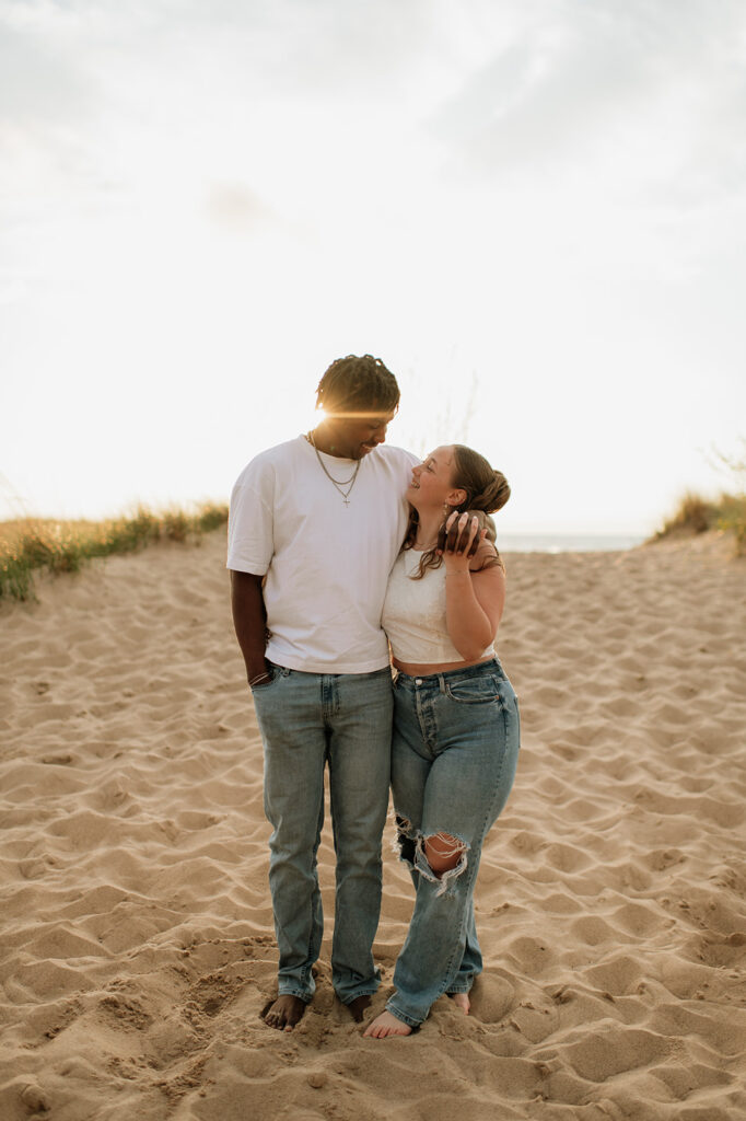 Couple walking along the beach in Southwest Michigan for their outdoor engagement photos at sunset