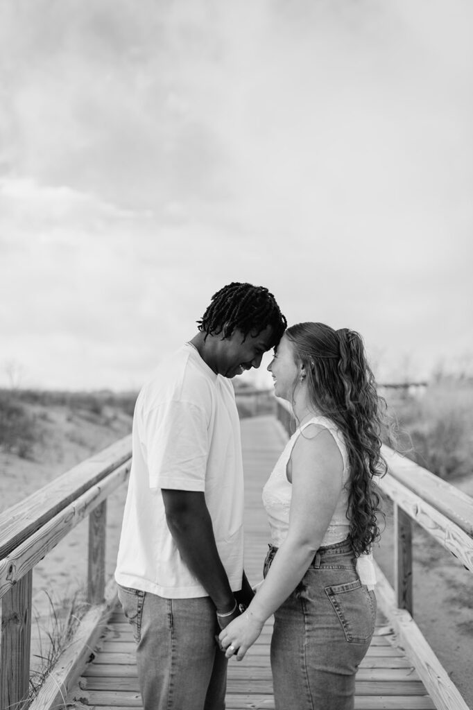 Black and white photo of a couple posing on the boardwalk for their Southwest Michigan engagement photos at New Buffalo Beach