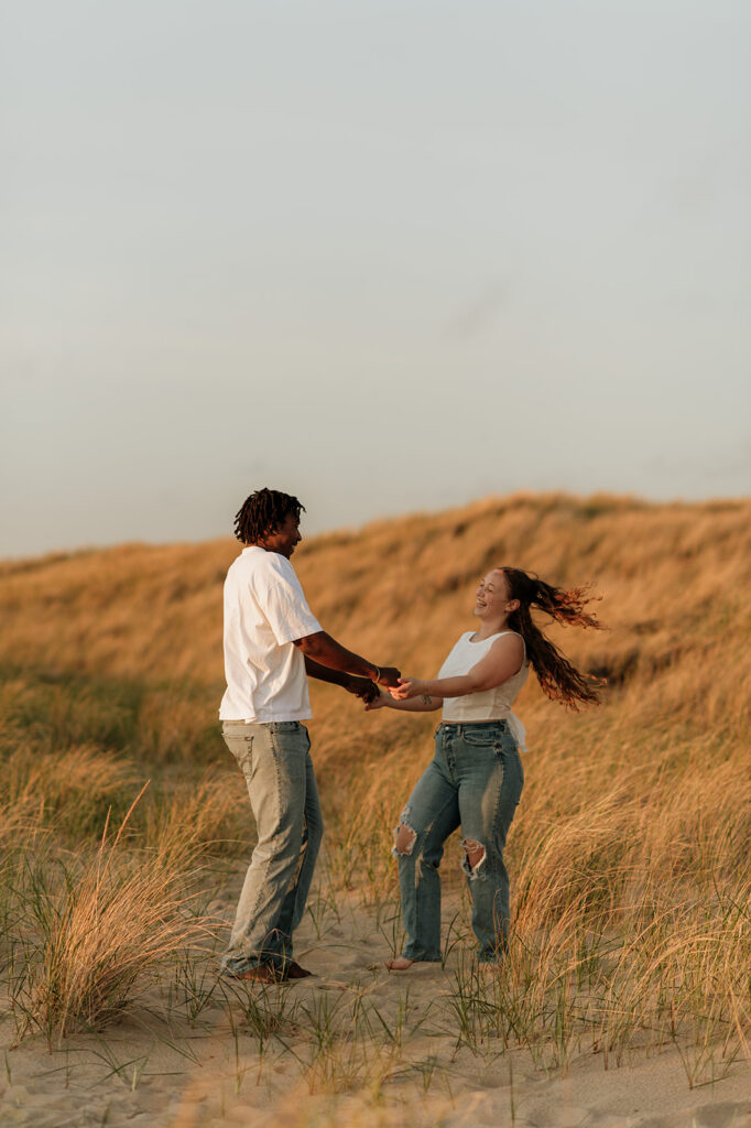 Couple being playful for their sunset beach engagement photos in Southwest Michigan