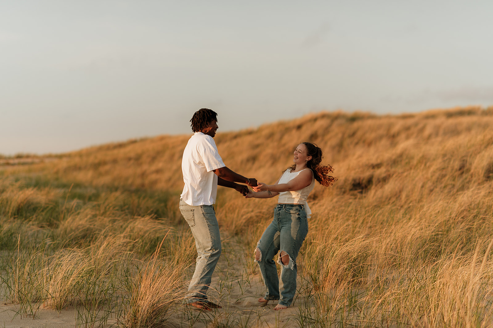 Couple being playful for their sunset beach engagement photos in Southwest Michigan