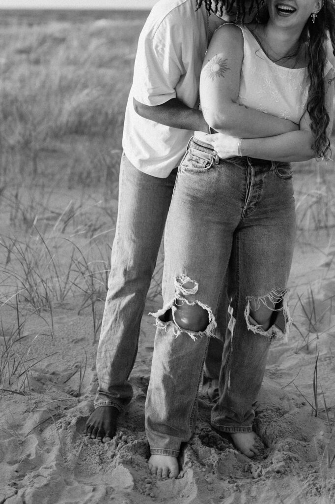 Black and white photo of a couple being playful during their beach engagement shoot