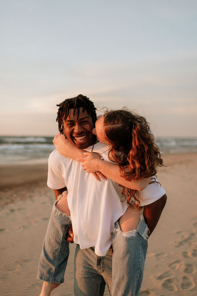 Man giving his fiancé a piggyback ride on the beach