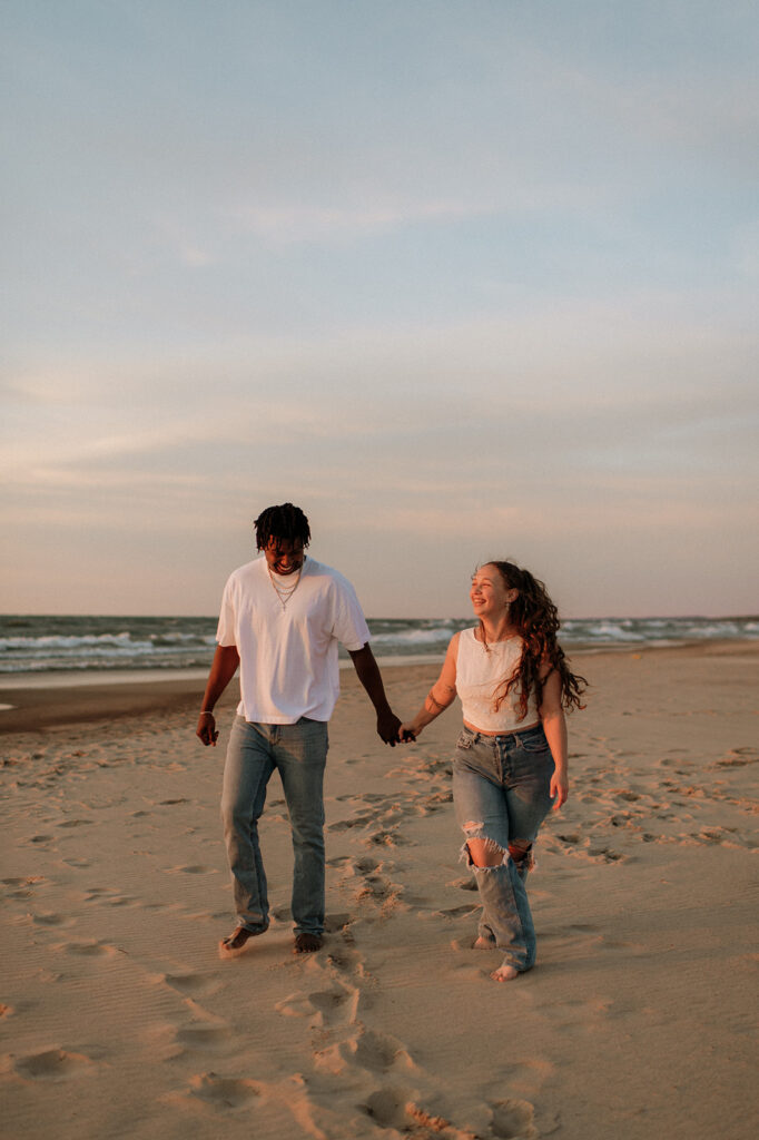 Couple walking the beach and holding hands at sunset