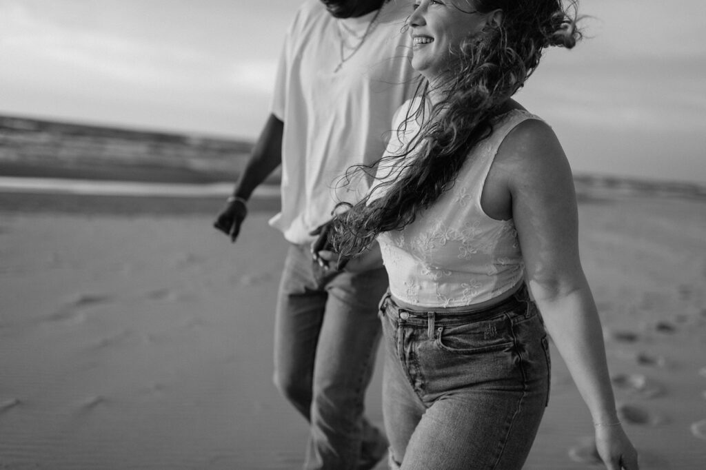 Black and white photo of a couple walking along the beach in Michigan