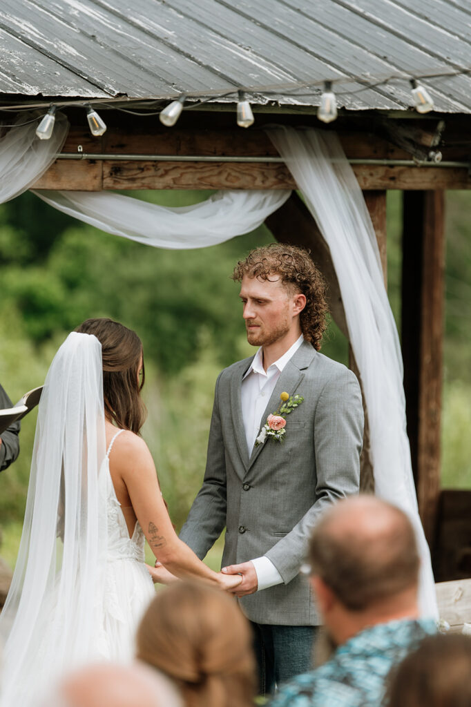 Close up of the bride and groom holding hands during their outdoor 5C Farms wedding ceremony in Albion, Indiana