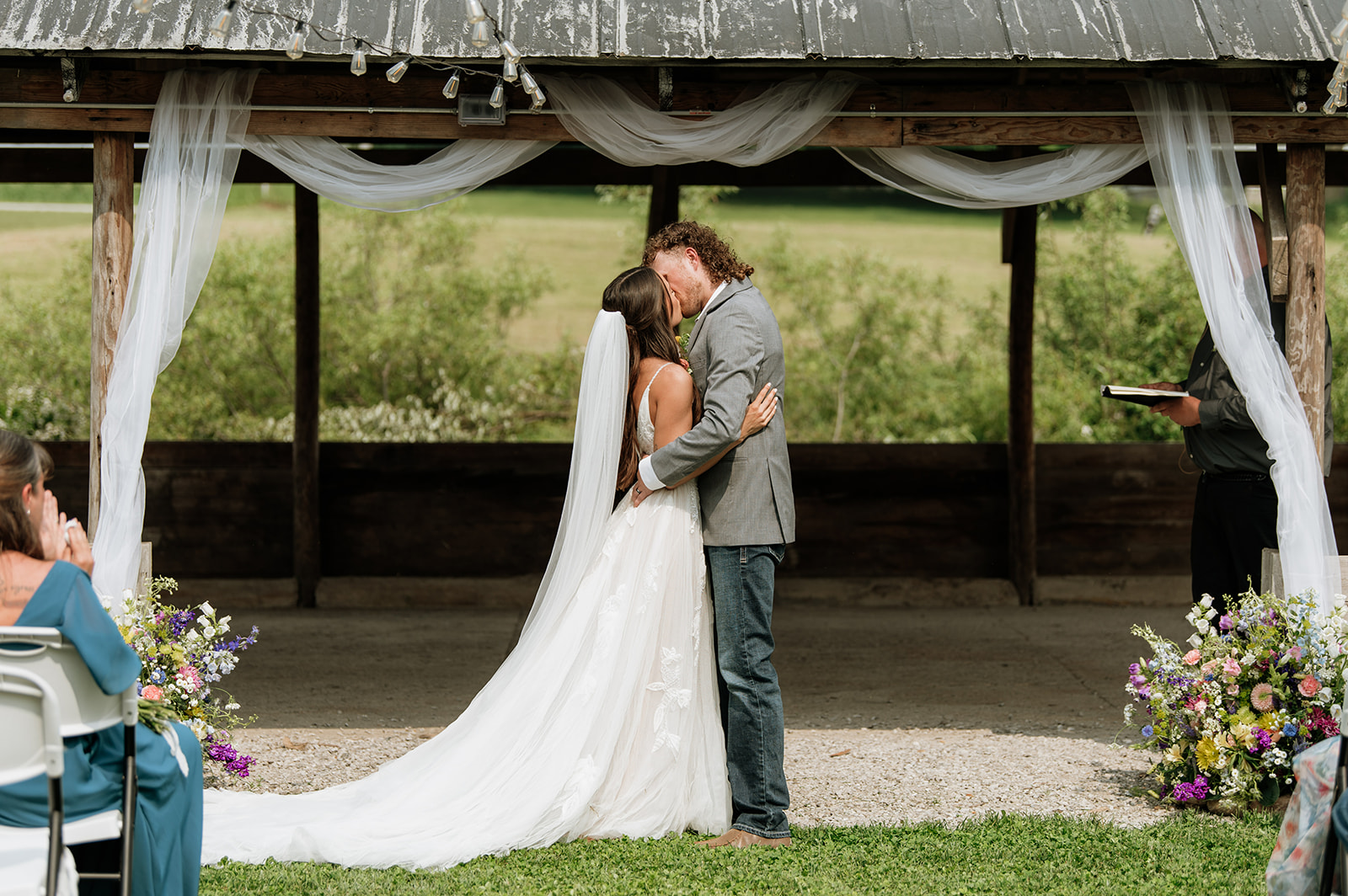 Bride and groom sharing their first kiss under the wooden shelter at 5C Farms ceremony space.