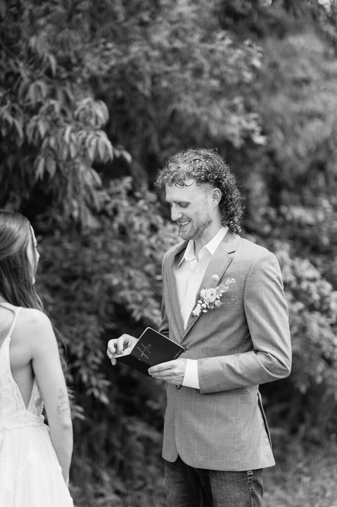 Black and white photo of a groom reading his vows to his bride