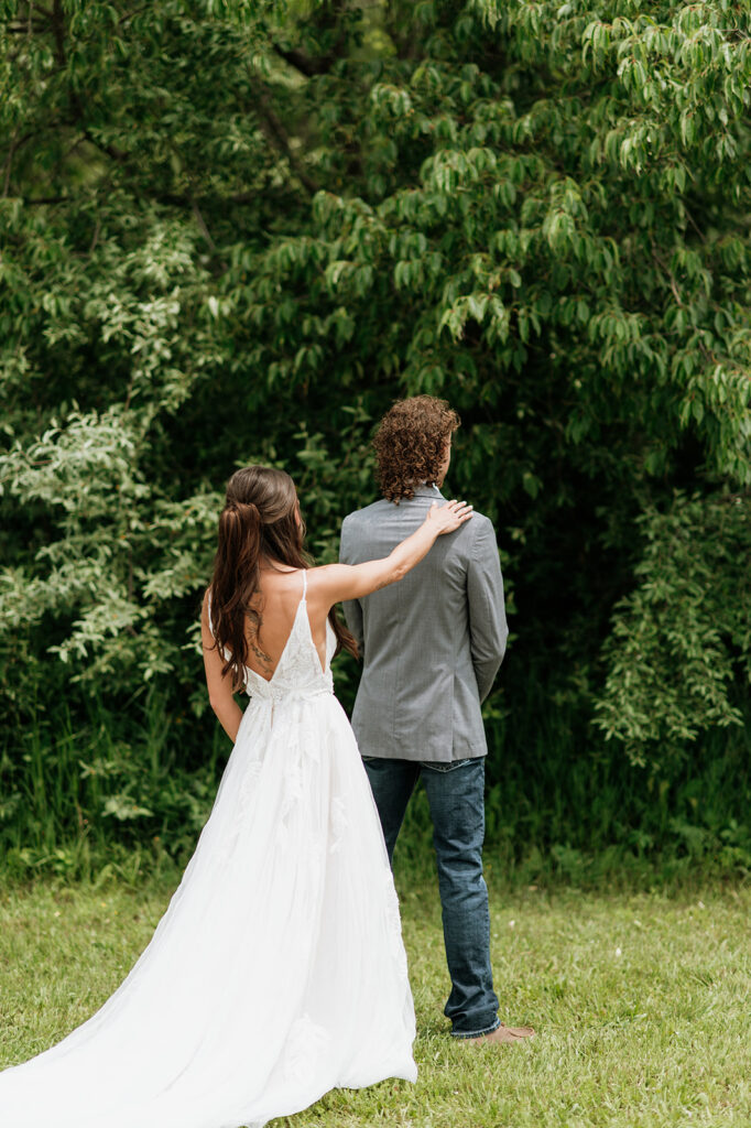 Bride tapping her groom on the shoulders for their first look