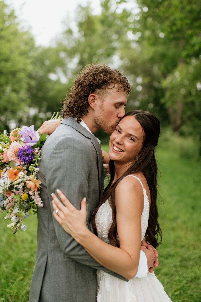 Groom kissing his brides head during their outdoor portraits on the property of 5c Farms - Premier Indiana barn wedding venue