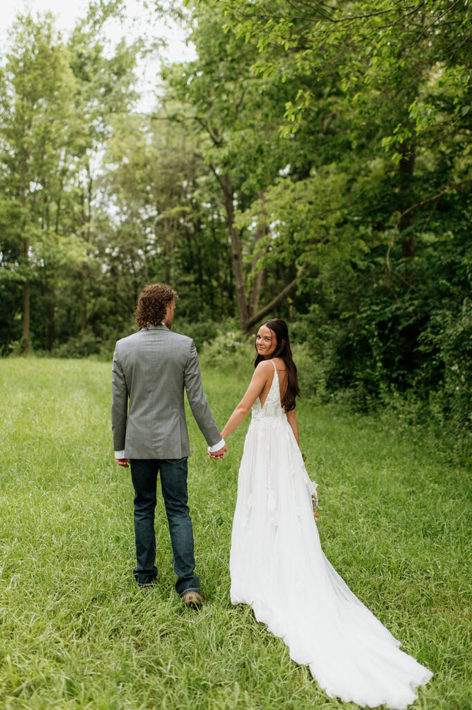 Bride and groom walking hand in hand outdoors for their portraits on the property of 5c Farms - Premier Indiana barn wedding venue