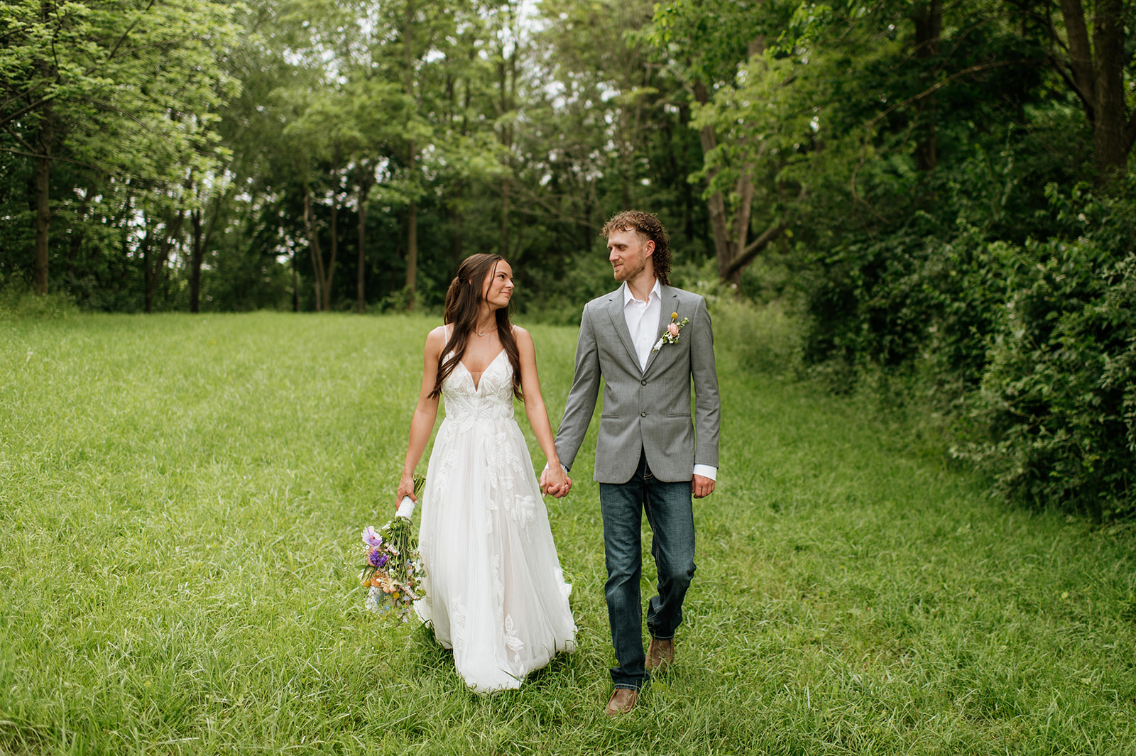 Bride and groom walking hand in hand for their outdoor portraits  on the property of 5c Farms - Premier Indiana barn wedding venue