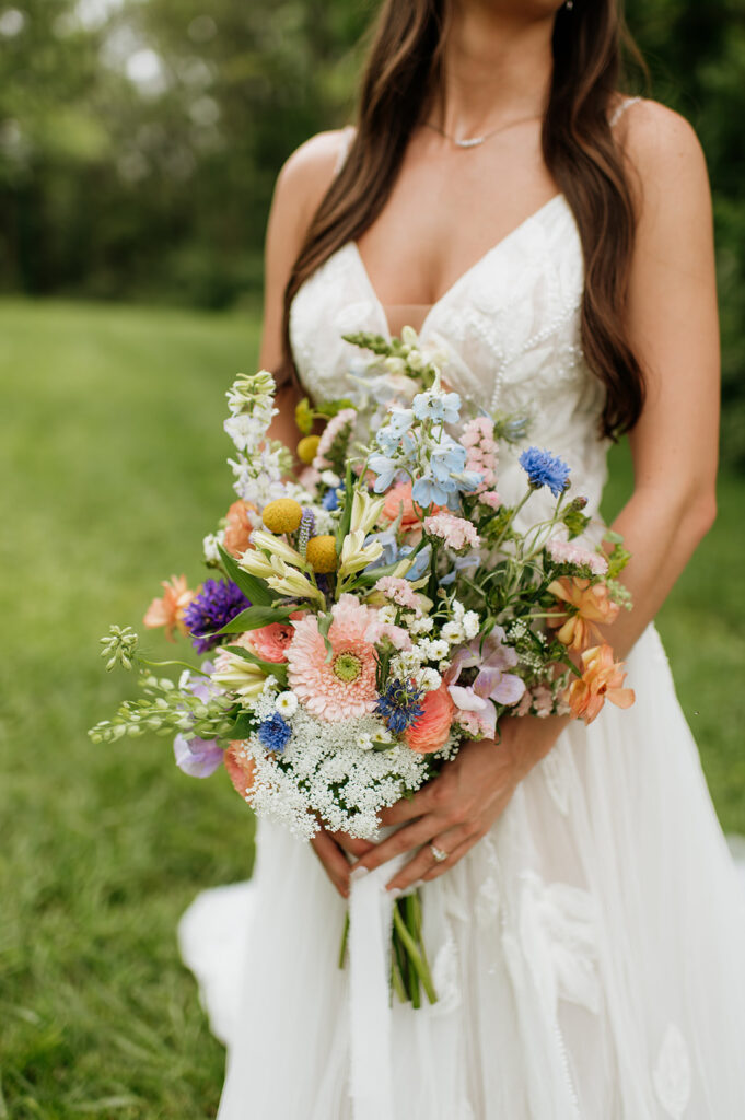 Close up shot of a bride holding colorful florals for her summer wedding